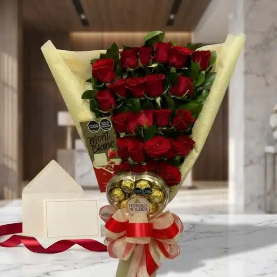 Arreglo floral de rosas rojas con chocolates Ferrero Rocher y tarjeta de regalo en un elegante entorno de mármol.