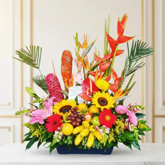 Arreglo Floral con Frutas Hawai: Exotismo y Frescura en tu Hogar Arreglo floral exótico con heliconias, girasoles, lirios, anturios y frutas tropicales como plátanos, uvas, manzanas y limone