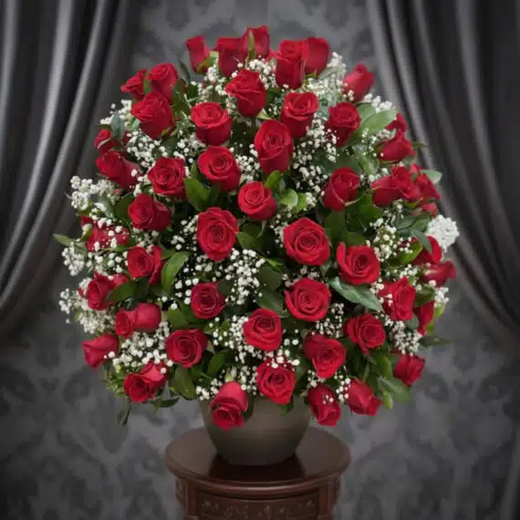Impresionante arreglo floral de rosas rojas frescas y gypsophila en un jarrón gris sobre una mesa de madera, con un fondo ele