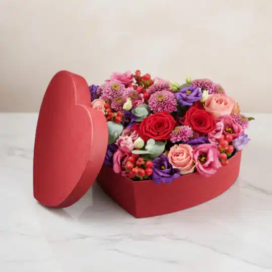 Arreglo floral ZITA en caja de corazón roja con rosas rojas, rosadas y flores mixtas, ideal para regalar en ocasiones especia