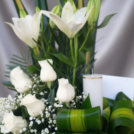 Fotografía macro premium de Arreglo Fúnebre Claridad con lirios y rosas blancas, rocío sutil, cinta satinada y follaje verde.
