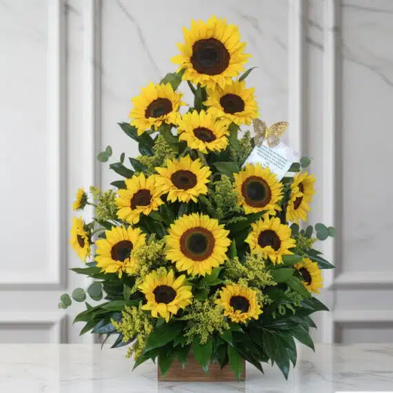 Arreglo con Girasoles Radiante: Frescura y Elegancia para tu Hogar Arreglo floral de girasoles radiantes en un jarrón de madera, sobre una superficie de mármol, con un fondo elegante y luminos