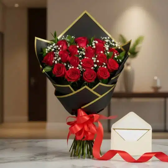 Bouquet de rosas rojas frescas y gypsophila envuelto en papel negro y dorado, atado con una cinta de satén rojo, sobre una su