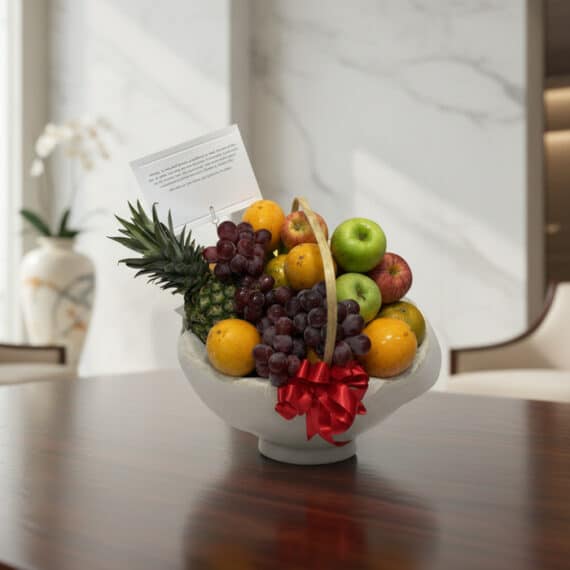 Canasta de Frutas Gourmet: El Regalo Saludable y Elegante Perfecto Canasta de frutas gourmet con piña, uvas, manzanas y naranjas, sobre una mesa de madera pulida en un entorno elegante.