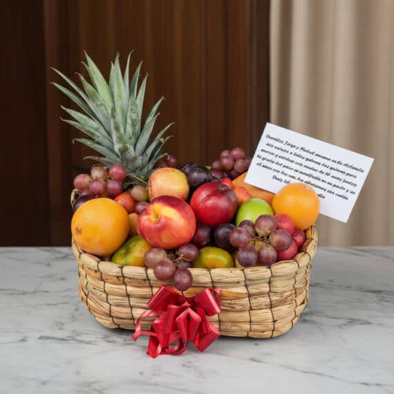 Canasta de Frutas Musca: Frescura y Elegancia para Regalos Especiales Canasta de frutas Musca con piña, uvas, manzanas, naranjas y duraznos, presentada en un entorno elegante con fondo de madera