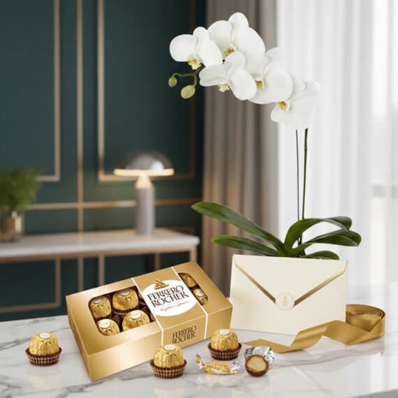 Arreglo MARELY con orquídea Phalaenopsis blanca, caja de chocolates Ferrero Rocher, tarjeta de regalo y cinta dorada sobre má