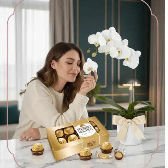 Mujer joven y elegante admirando una orquídea Phalaenopsis blanca con chocolates Ferrero Rocher en un ambiente de hogar lujos